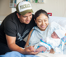 Happy couple holding their newborn. Link to Life Stage Gift Planner Under Age 60 Situations.